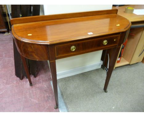 An Edwardian inlaid mahogany single drawer side table with bow sides and line inlaid tapering supports on brass cup and casto