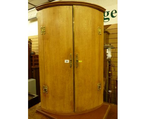 A light oak craftsman made reproduction two door bow front hanging corner cupboard with brass 'H' hinges and escutcheons etc