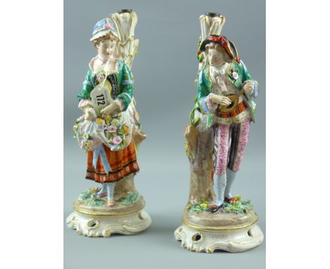 A pair of Continental porcelain figural stands showing a well dressed young man playing a lute and a bonneted young woman car