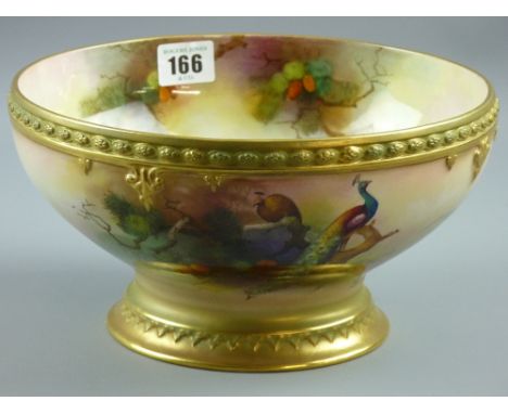 A large Royal Worcester footed bowl, hand painted by Albert J Schuck of peacocks upon pine tree branches with raised pattern 