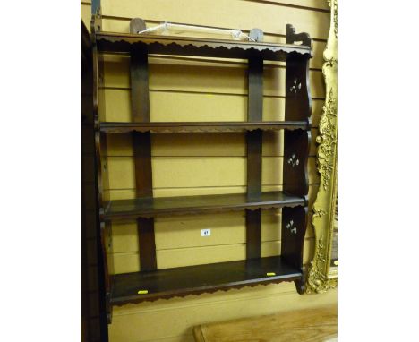 An Edwardian mahogany four shelf wall rack, each shelf with a shaped apron and with carved floral ends