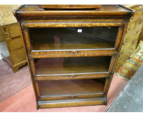 A Globe Wernicke style three shelf bookcase with plain glass panels and top hinges and with narrow top gallery