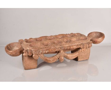 An African Mancala Board, the hand carved wooden game board on broad bracket feet, 82cm L x 28cm W x 19cm H
