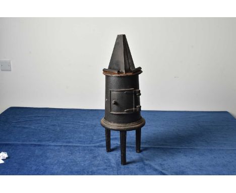 A small Iron Stove, unnamed, on tripod base, door to front with chimney hole to the reverse, with stand for three irons to th