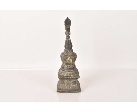 An Antique Tibetan Buddha Stupa Pagoda Tower, in bronze, with a small figure of a seated Buddha embedded in clay, having embo