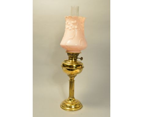 A BRASS CORINTHIAN COLUMN OIL LAMP, having brass reservoir, on circular brass foot, floral opaque glass shade, and clear chim