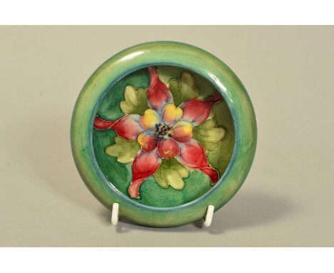 A MOORCROFT POTTERY LIPPED TRINKET DISH, 'Columbine' pattern on green ground, impressed marks to base, diameter internally 8.