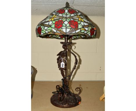 A TIFFANY STYLE TABLE LAMP, having leaf decoration around the support, shade having red rose and green leaves decoration, tot