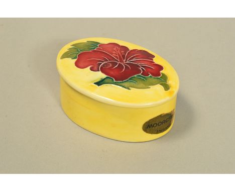 A SMALL MOORCROFT POTTERY OVAL TRINKET BOX AND COVER, 'Hibiscus' pattern on yellow ground, impressed marks to base, length 7.