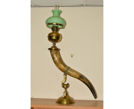 A NOVELTY BRASS AND HORN SHAPED OIL LAMP, raised on a fox's head brass stand, with green glass shade and clear chimney, appro