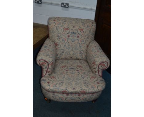 A HOWARD AND SONS STYLE EARLY 20TH CENTURY ARMCHAIR, scrolled arms and low back on turned legs and ceramic casters, width 89c