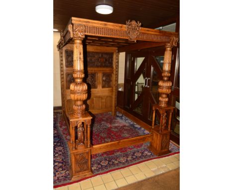 A REPRODUCTION OAK 5FT FOUR POSTER FULL TESTER BED, the headboard formed of three seperate panels, the upper panel carved wit