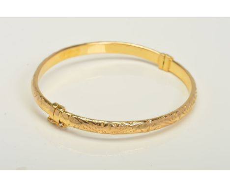 A 9CT GOLD HINGED BANGLE, with banded and scrolling decoration to the full bangle, the sprung hinge with a figure of eight cl