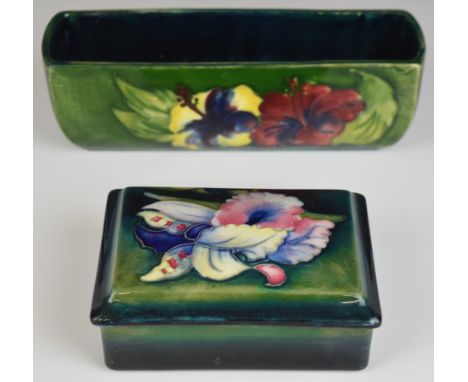 Moorcroft covered box decorated in the Orchid pattern and a trough with Hibiscus decoration, length 19.5cm