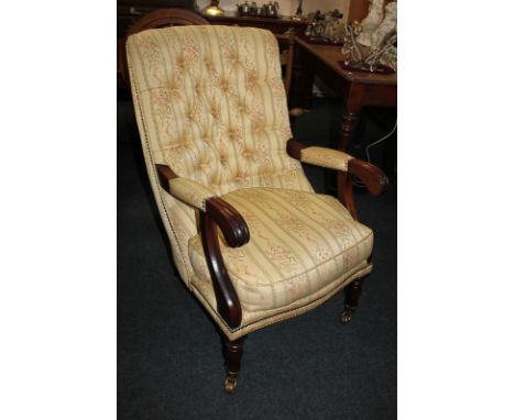 A reproduction mahogany button backed armchair in striped cream upholstery, with padded open arms, on turned legs and castors