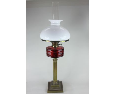 A Victorian brass column oil lamp with cranberry glass well, and white glass shade and funnel 79cm high
