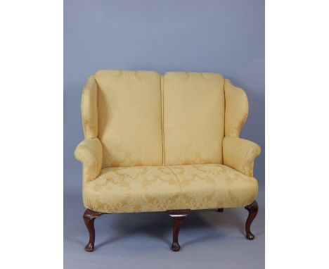 George II style wing upholstered two seat chair back sofa, raised on cabriole legs ending in pad feet, 144cm w.