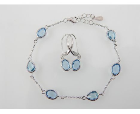 A silver bracelet set with six pearl drop light blue stones together with a pair of matching earrings.