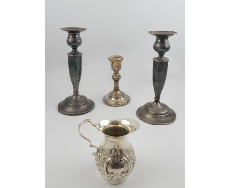 Sterling silver pair of candlesticks, 20cm and another single stick and an Edwardian silver cream jug with repousse floral de