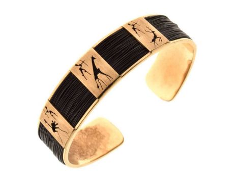 South African yellow metal (375) bangle, pierced with animals and huntsmen, on black fibre ground (reputedly elephant whisker