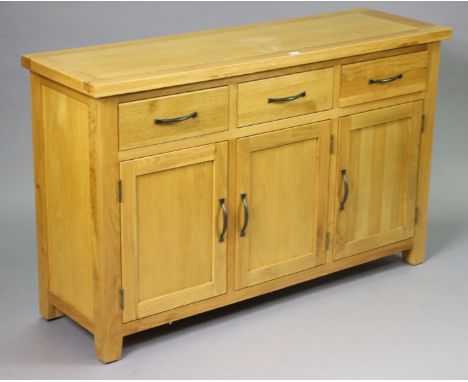 A light oak sideboard fitted three frieze drawers above cupboard enclosed by three panel doors, 136.5cm wide x 86cm high x 43