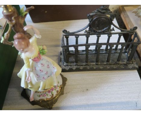 A metal letter rack, with classical details, together with a porcelain lamp base of a girl by a tree