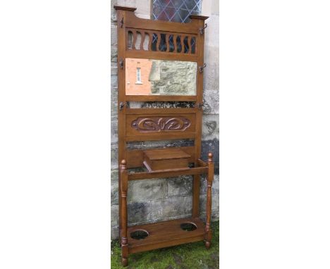 An Edwardian carved oak hall stand, with pierced section above a rectangular mirror, fitted with a glove box and stick stands