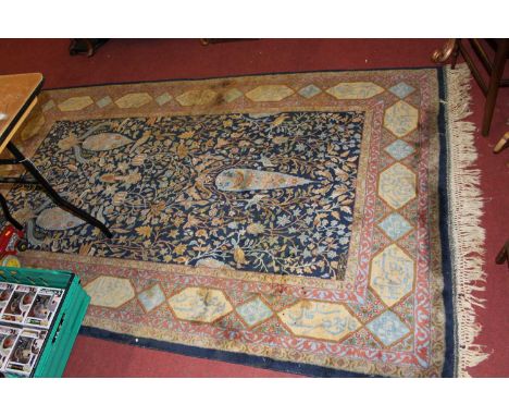 A Persian woollen blue ground rug, the heavily decorated central ground within trailing tramline borders including panels wit