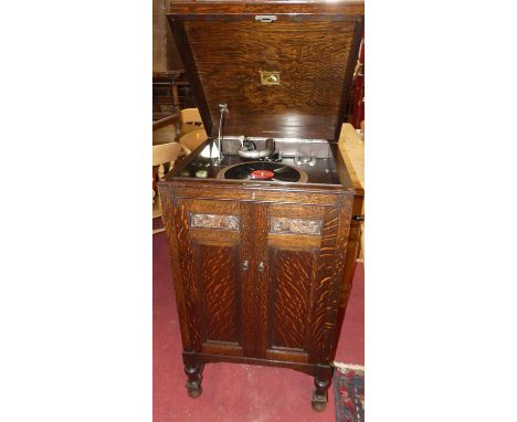 A 1930s 'His Master's Voice' oak freestanding gramophone, the hinged cover with gramophone deck over twin cupboard doors, w.5