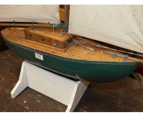 A wooden kit built model pond yacht with canvas sails, housed on wooden display plinth