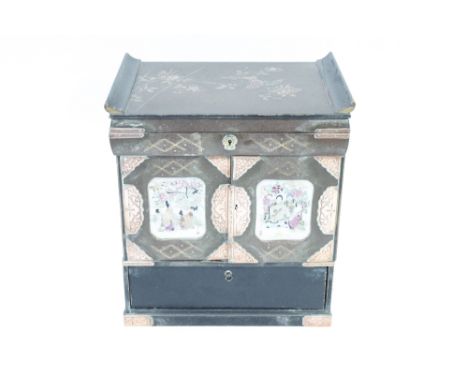 An early 20th century Japanese lacquered table top cabinet, with open out doors each with a ceramic panel, the interior fitte