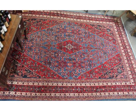 A large 20th century carpet, on a red ground, with central diamond motif and repeater boarder, 350cm x 270cm