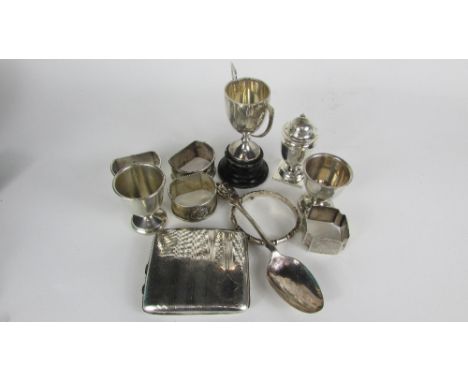 A collection of silver items, comprising; two egg cups; a cigarette case; three D shaped napkin rings with a monogrammed life