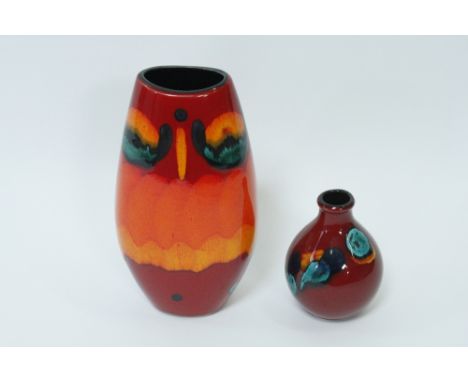 A Poole pottery vase on a red background, 26cm high, along with a Poole square vase.13.5cm high