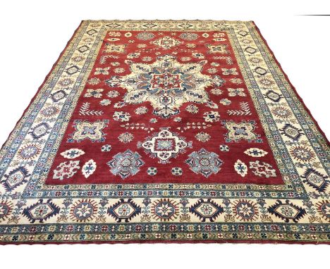 KAZAK CARPET, 350cm x 250cm, central medallion on a ruby field of geometric motifs within complimentary borders.