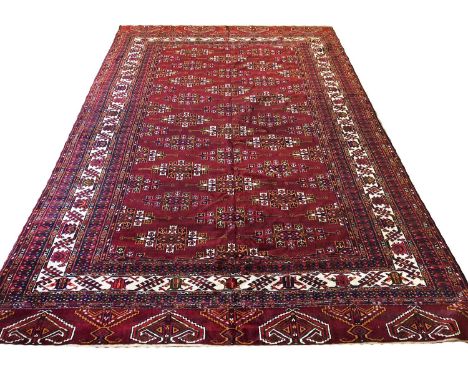 TURKMAN YOMUT CARPET, 315cm x 210cm, repeat gul design on a deep ruby field within geometric guard stripes and matching end b
