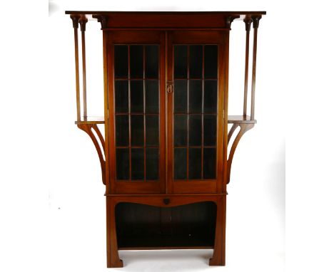 An Art Nouveau mahogany bookcase of stylised form with lattice-glazed doors, flanked by projecting side shelves and shaped al