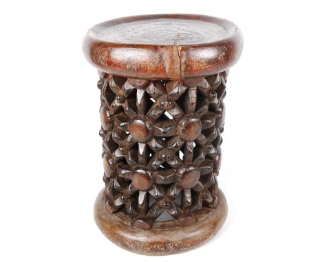 A small African stained wood drum-shaped stool with lattice pierced carved side, carved from a single piece of timber, height