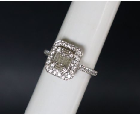 An 18ct white gold diamond cluster ring set with baguette and round brilliant cut diamonds to the top and shoulders, size M, 