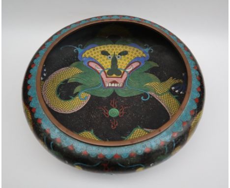 A Japanese cloisonne enamel bowl, decorated to the centre with a dragon to a black cloud ground, the sides similarly decorate