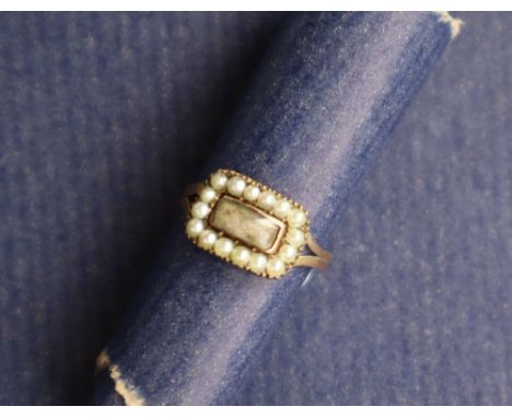 A 19th century yellow metal mourning ring set with a rectangular panel surrounded by half section pearls, size N approximatel