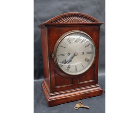 A late 19th / early 20th century oak bracket clock, with a domed top and pedestal base, the silvered dial with Roman numerals