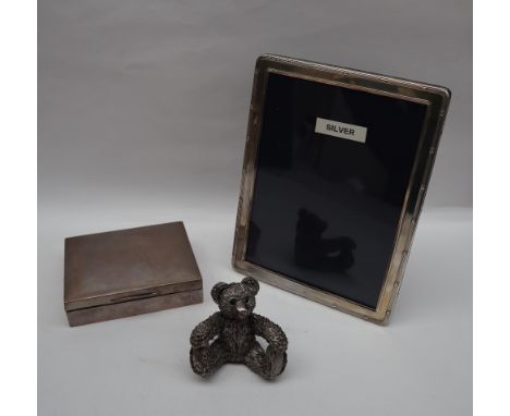 A silver cigarette box of rectangular form together with a silver photograph frame and a silver teddy bear figure