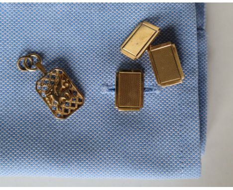 A pair of 9ct yellow gold cufflinks, of rectangular form with engine turned decoration, together with a 9ct gold dragon adorn