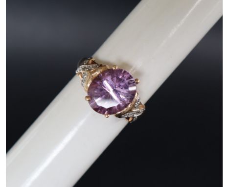 An amethyst and diamond and dress ring, set with a central oval faceted amethyst the shoulders set with round brilliant cut d