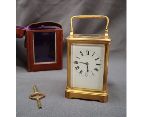 A 19th century French brass carriage timepiece with a rectangular enamel dial and Roman numerals, 18cm high in a leather carr