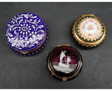 A blue enamel pill box and cover of circular form decorated with white flower heads and leaves to a gilt interior, 6.5cm diam
