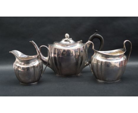 A George V silver three piece tea set, comprising a teapot with acorn finial and shaped oval body, matching cream jug and twi