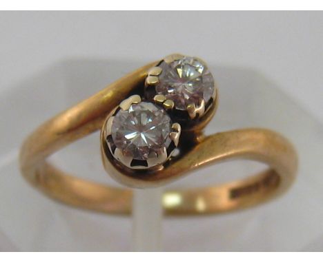 A 9 carat yellow gold and two stone diamond cross over ring, the two brilliants each 0.16 carat, finger size H/I, 2 gms
