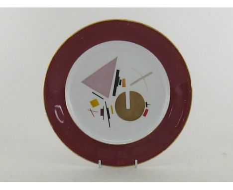 An early Soviet Russian ceramic plate , the modernist design over the glaze within a wide red/brown border, the underside wit
